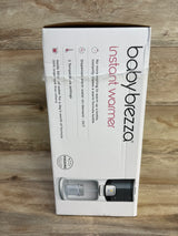 Front of Baby Brezza bottle warmer box showing instant warmer text and features, on demand warm water and 3 temps, on wood background
