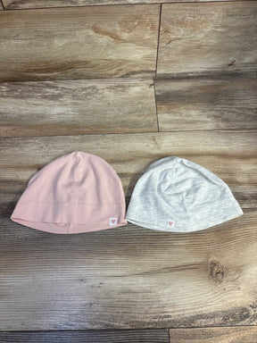 Pink and gray baby beanies with heart tags on wooden floor