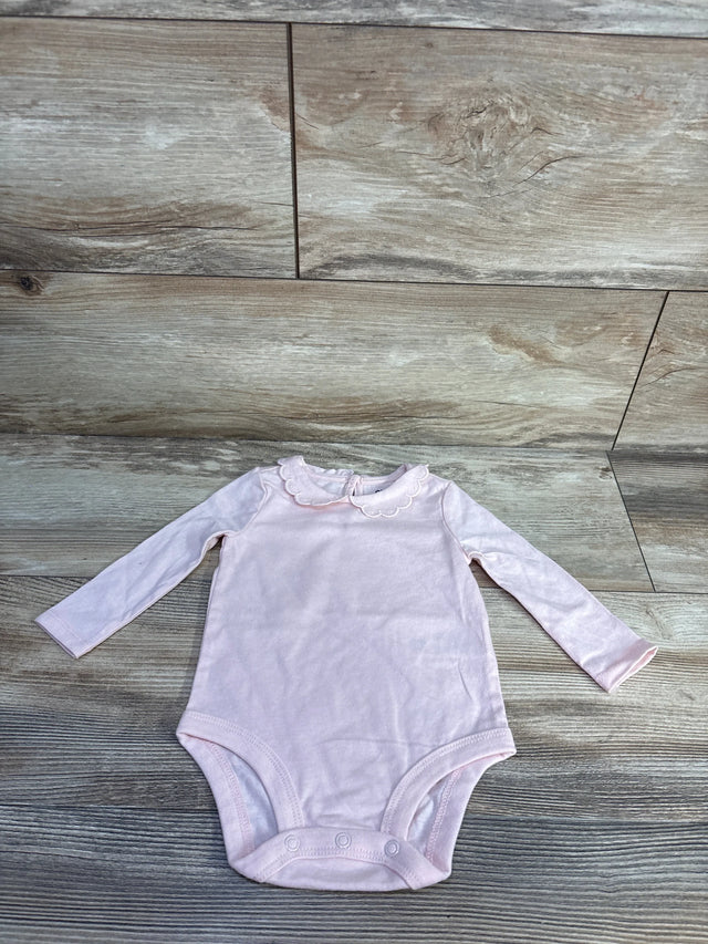 Flat lay of pink OshKosh long-sleeve baby bodysuit showing scalloped Peter Pan collar and three snap closures on wood plank background