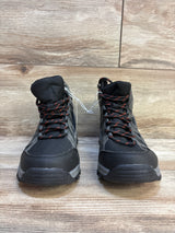 Pair of black and gray kids' hiking boots with red laces on wood floor