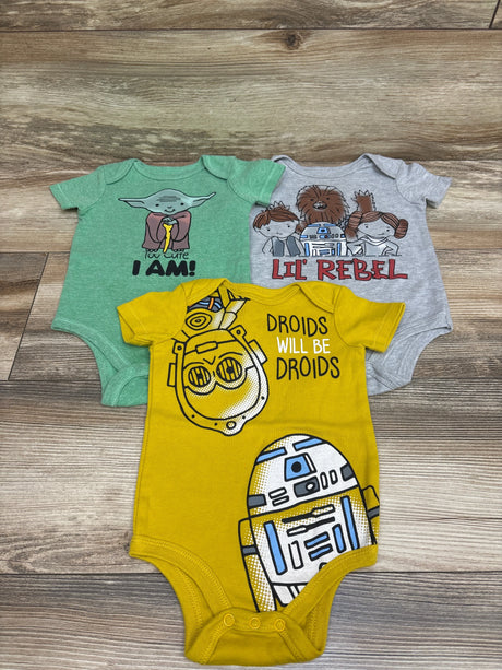 Top view of Star Wars 3-pack baby bodysuits in green, gray, and yellow, size 12 months, with character graphics on a wood floor