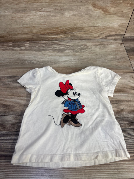 Front view of ivory Baby Gap Minnie Mouse toddler shirt with centered Minnie graphic, red bow, glitter shoes on wood