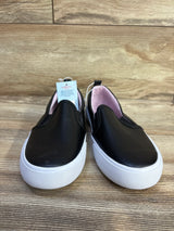 Front view of Cat & Jack Hailey slip-on toddler sneakers, black upper with white platform soles and pink lining on wood floor