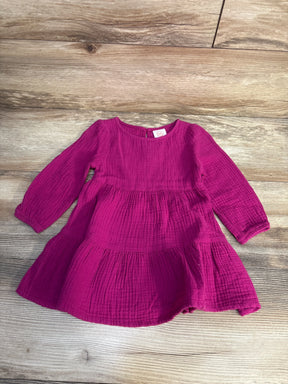 Magenta long sleeve baby dress with tiered skirt, textured cotton, on wood background