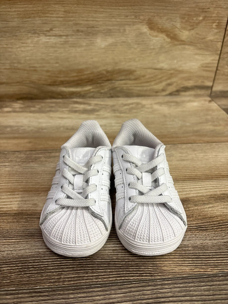 Front view of Adidas Superstar El I sneakers in white, size 5C, showcasing shell toes and laces on a wood surface