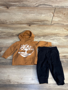 Toddler outfit with brown tree print hoodie and black pants on wood background
