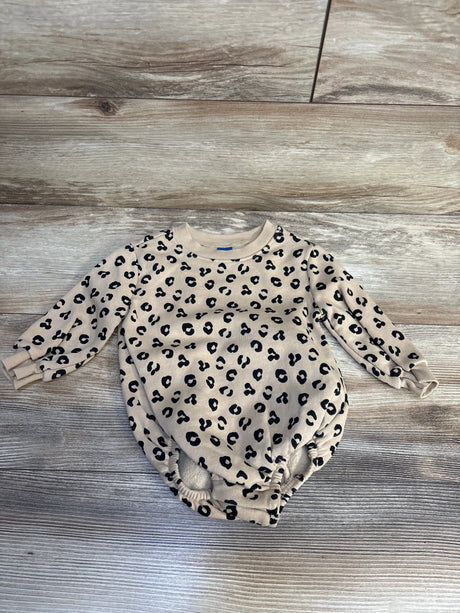 Beige baby onesie with black leopard print, long sleeves, laid on wood floor