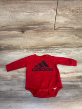 Red long sleeve Adidas baby bodysuit with black logo on wooden floor