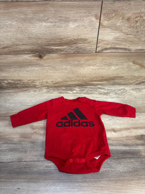 Red long sleeve Adidas baby bodysuit with black logo on wooden floor