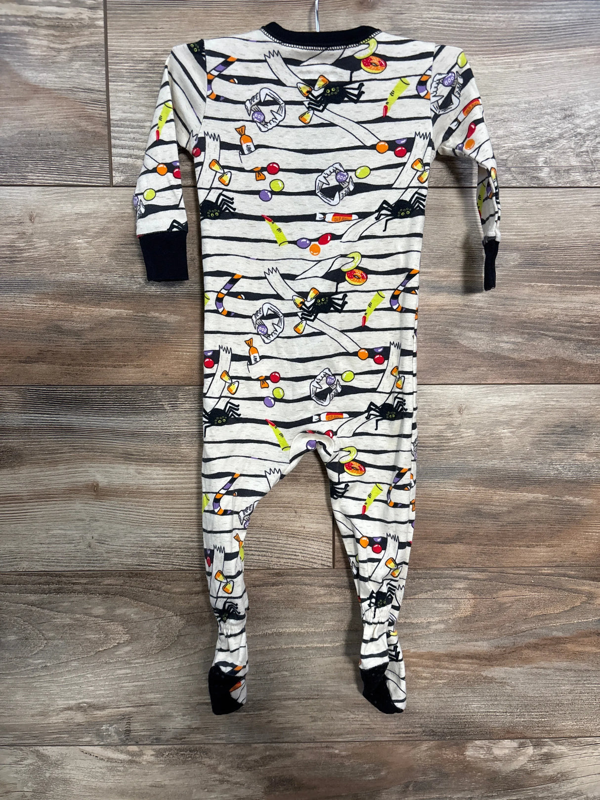 Halloween-themed baby footed pajamas with candy and spider print on striped background