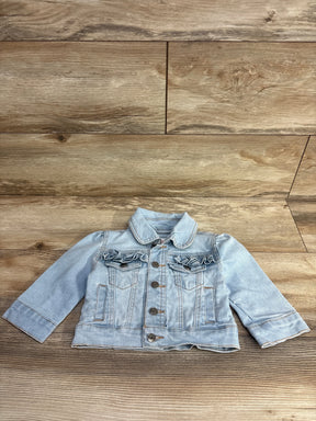 Light blue toddler denim jacket with ruffled chest pockets on wood background