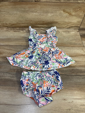 Top view of baby 2-piece cotton dress and bloomers with multicolor tropical print and ruffled straps on wood background