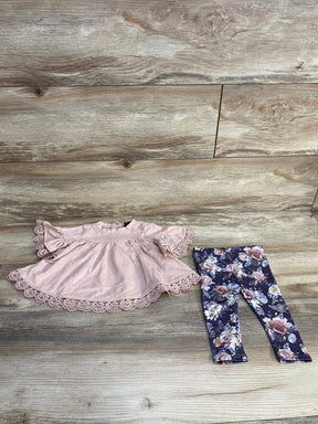 Flat lay of Cynthia Rowley 2-piece baby top and leggings showcasing pink lace-trim swing top and navy floral leggings on light wood background