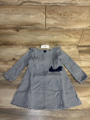 Girls' houndstooth long sleeve dress with navy bow, laid flat on wood floor.