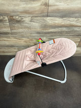 Angled view of Baby Bjorn Bouncer Bliss in dusty pink showing quilted petal seat and toy bar on wood floor
