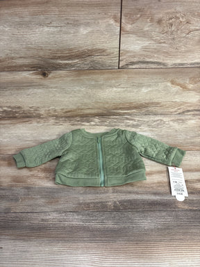 Green quilted baby jacket with zipper and price tag on wooden floor