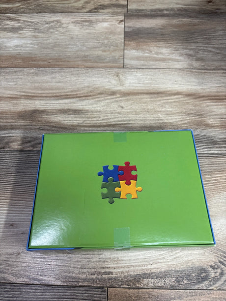 Front view of zhiseoyi 300pc Happy Puppies jigsaw puzzle box showcasing a green cover with colorful puzzle pieces on a wood surface