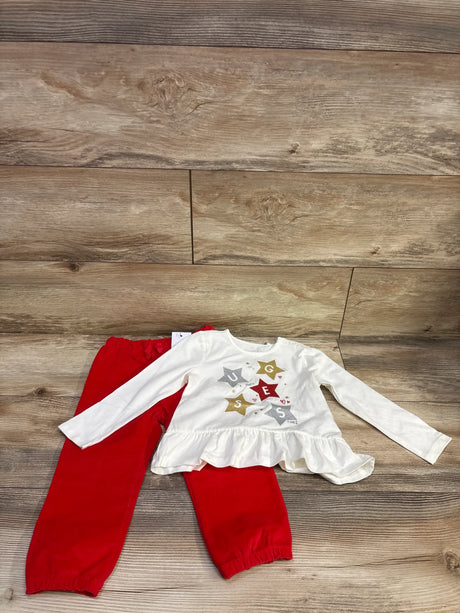 Top view of a white Guess peplum shirt and red pants set showcasing a ruffled hem and long sleeves on a wood floor