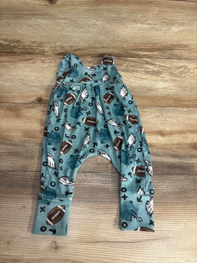 Baby romper with football, helmet, and play symbols on blue fabric, laid on wood