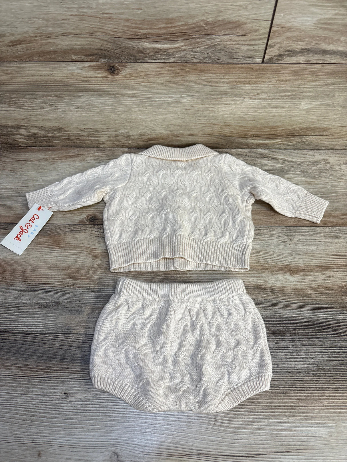 Cream cable knit baby sweater and bloomer set on wood floor, Cat & Jack brand