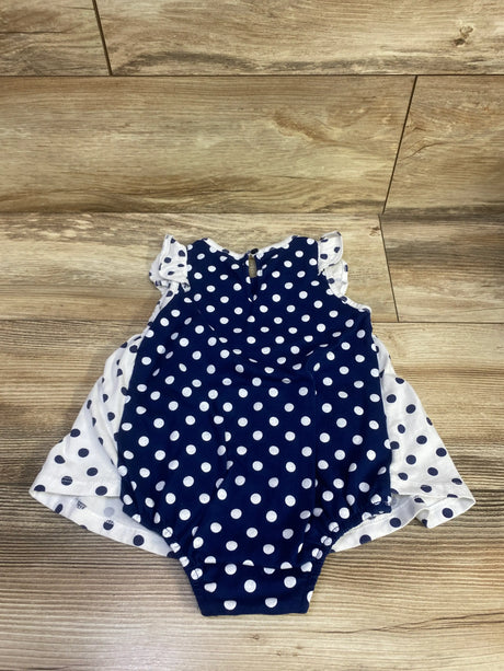 Front view of First Impressions polka dot bodysuit dress in navy and white with ruffled shoulders on a wood floor