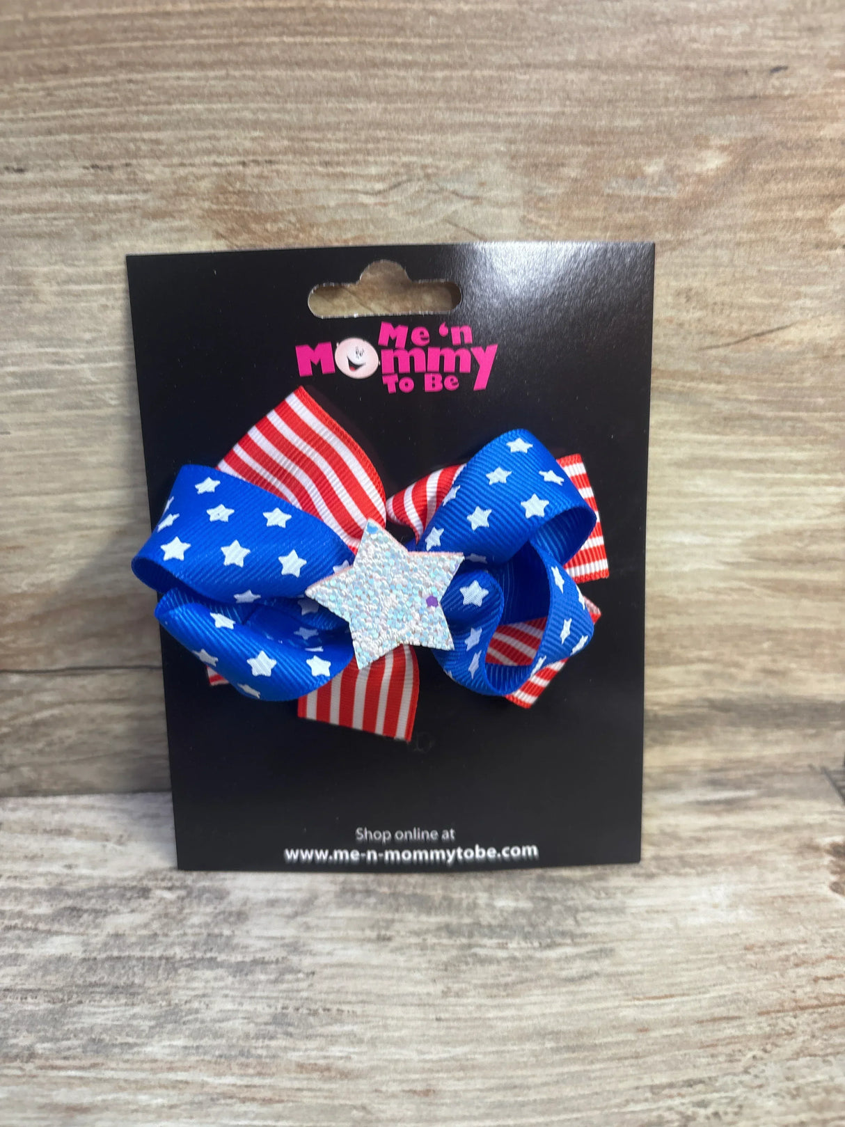 Front view of Fourth of July hair bow with red-and-white striped and blue star ribbons and glitter star center on black card