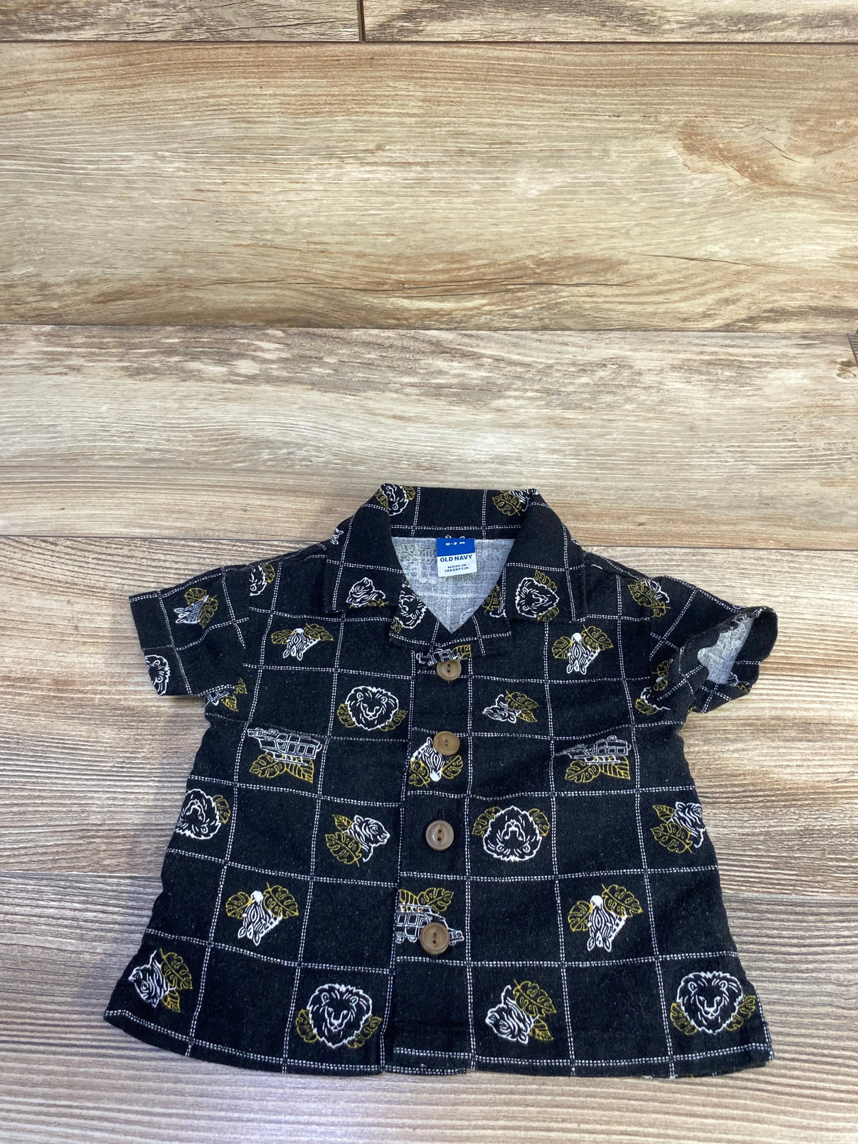 Flat lay of black Old Navy linen-blend newborn button-up shirt showing wooden buttons and grid print on wood background