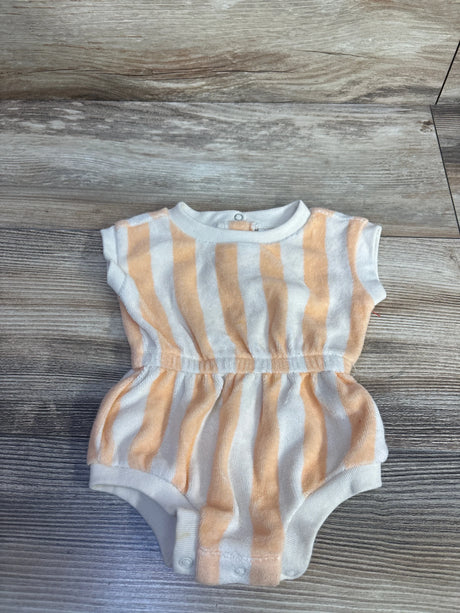 Flat lay of newborn terry cloth romper showcasing tan and white vertical stripes, elastic gathered waist and snap crotch on wood floor background