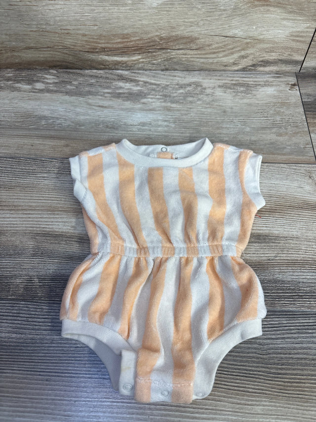 Flat lay of newborn terry cloth romper showcasing tan and white vertical stripes, elastic gathered waist and snap crotch on wood floor background