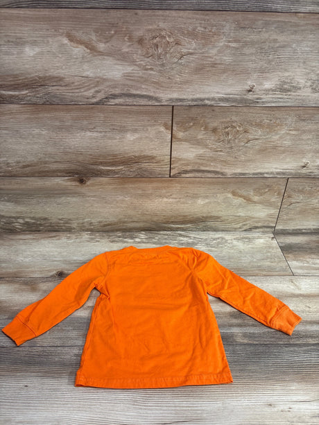 Back view of Carter’s Jack-O-Lantern shirt in orange, size 2T, showcasing long sleeves on a wood background