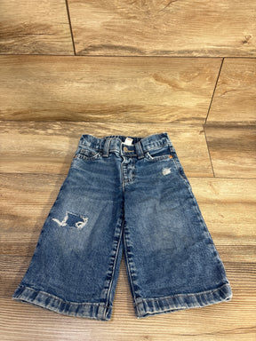 Flat lay of Cat & Jack distressed wide-leg jeans, front view showing faded blue denim and knee tear on wood floor background