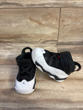 Angled front view of toddler Air Jordan 6 Rings sneakers in black/white/red showing Velcro strap and Jumpman logo on wood