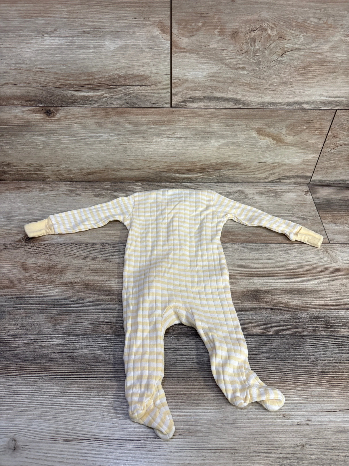 Flat-lay of Member's Mark striped footed sleeper, pale orange and white, showing long sleeves with fold-over mittens and enclosed feet on wood floor