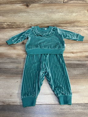 Green velvet toddler outfit with ruffled collar and ribbed cuffs on wood background