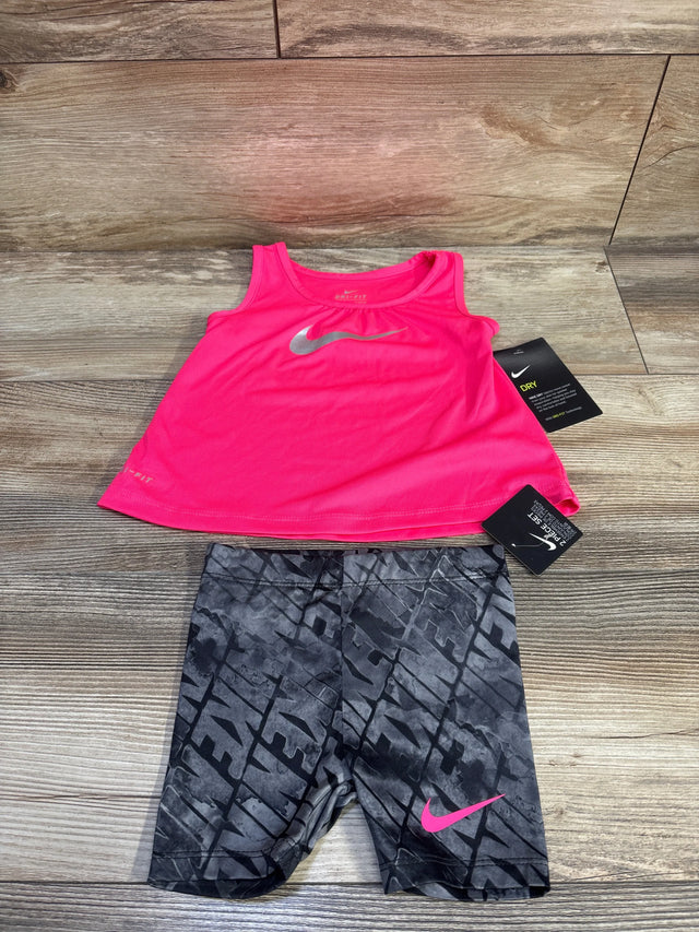 Flat-lay of Nike Dri-Fit tank and shorts showing hot pink tank with silver swoosh and gray shorts, pink swoosh on wood floor