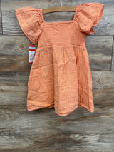 Peach toddler dress with flutter sleeves and gold stripes on wooden background