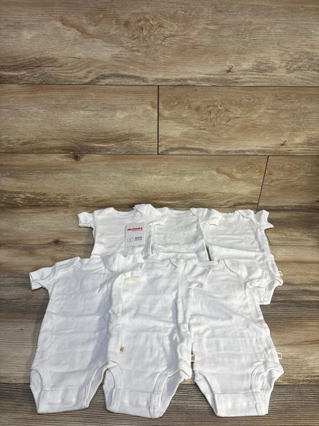 Front view of Huggies 6-pack white baby bodysuits showing lap shoulder necks and snap crotch closures on wood plank background