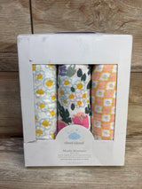 Front view of Cloud Island 3-pack muslin swaddle blankets showing three floral and geometric prints in a white display box on a wooden surface