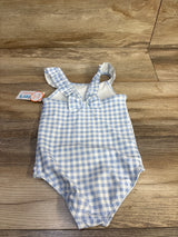 Flat-lay of blue and white gingham one-piece toddler swimsuit showing front bow and ruffled straps on wood background