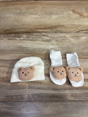 White baby hat and socks with teddy bear faces on wooden surface, children's apparel