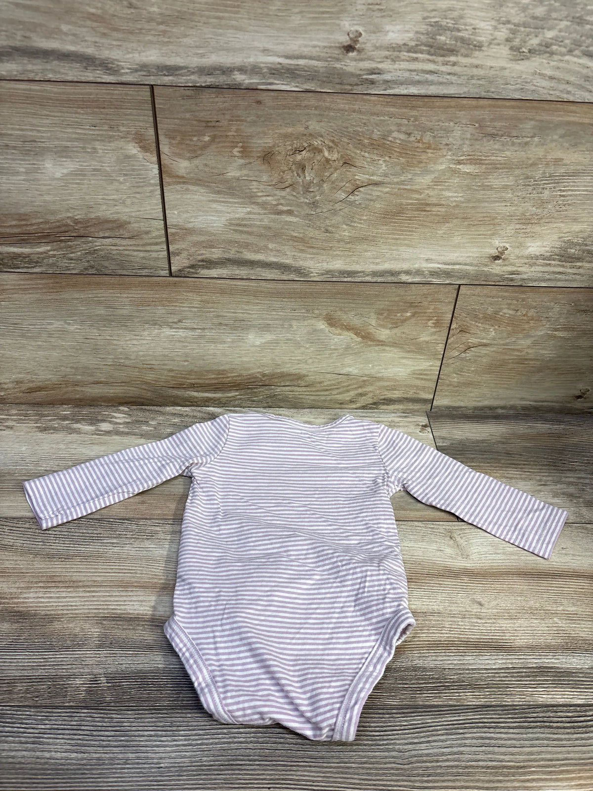 Back view of Carter’s Auntie’s Little Bean bodysuit showcasing purple and white stripes and long sleeves on a wood floor
