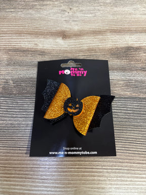 Glittery orange and black bat-shaped hair bow with jack-o'-lantern center, perfect for kids' Halloween outfits
