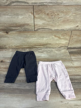 Top-down view of two Cloud Island newborn pull-on pants, grey and pale pink, showing elastic waist and cuffed ankles on wood
