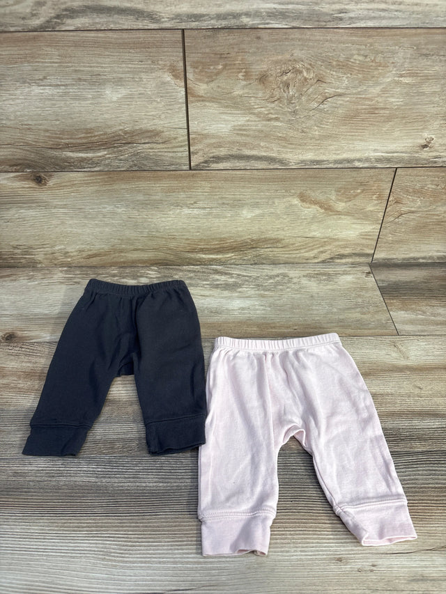 Top-down view of two Cloud Island newborn pull-on pants, grey and pale pink, showing elastic waist and cuffed ankles on wood