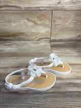 Angled view of white Bebe chiffon flower toddler sandal showcasing fabric flower embellishments and button back strap on wood backdrop
