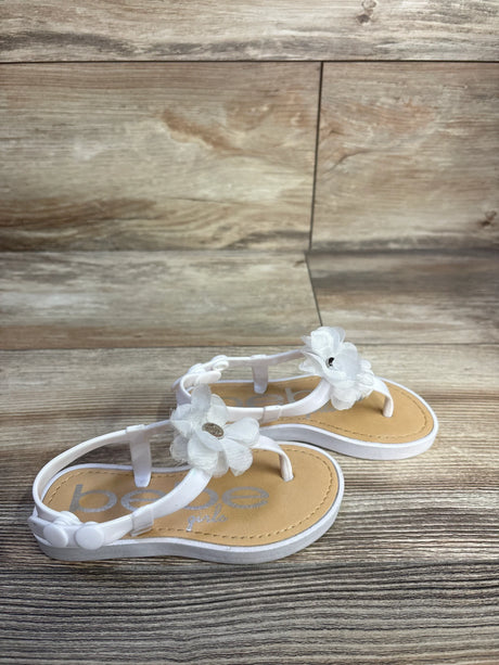 Angled view of white Bebe chiffon flower toddler sandal showcasing fabric flower embellishments and button back strap on wood backdrop