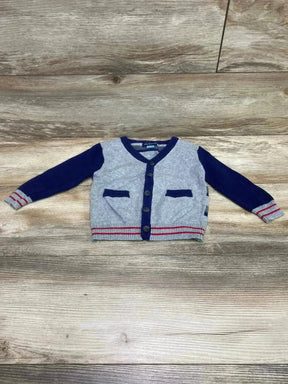 Flat lay of Andy and Evan toddler cardigan, gray body with navy sleeves, button front and red-striped hem on wood background
