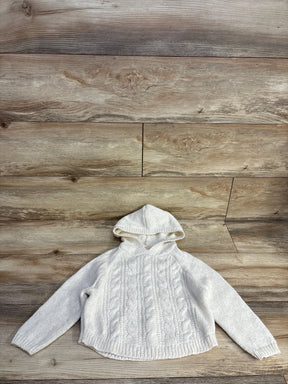 White knitted hooded sweater with cable patterns on wooden background