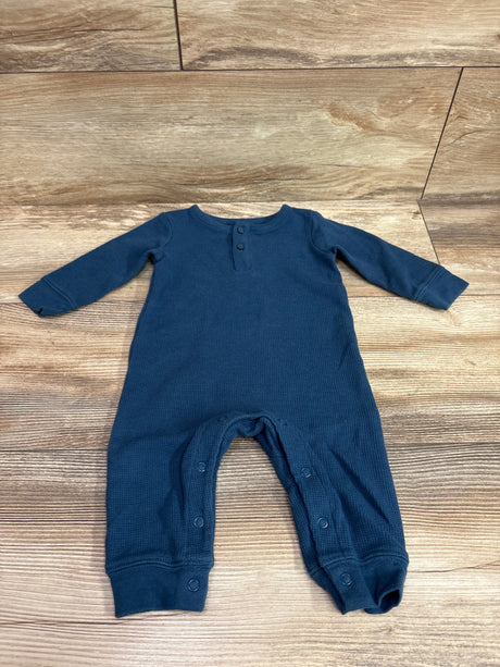 Flat lay of a blue Just One You waffle knit Henley coverall with long sleeves and snap closures on a wood floor