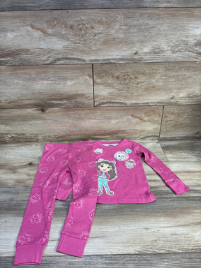 Front view of pink Gabby's Dollhouse 2-piece pajamas with character graphic top and matching cat-print pants on wood